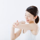 肘を見つめる女性